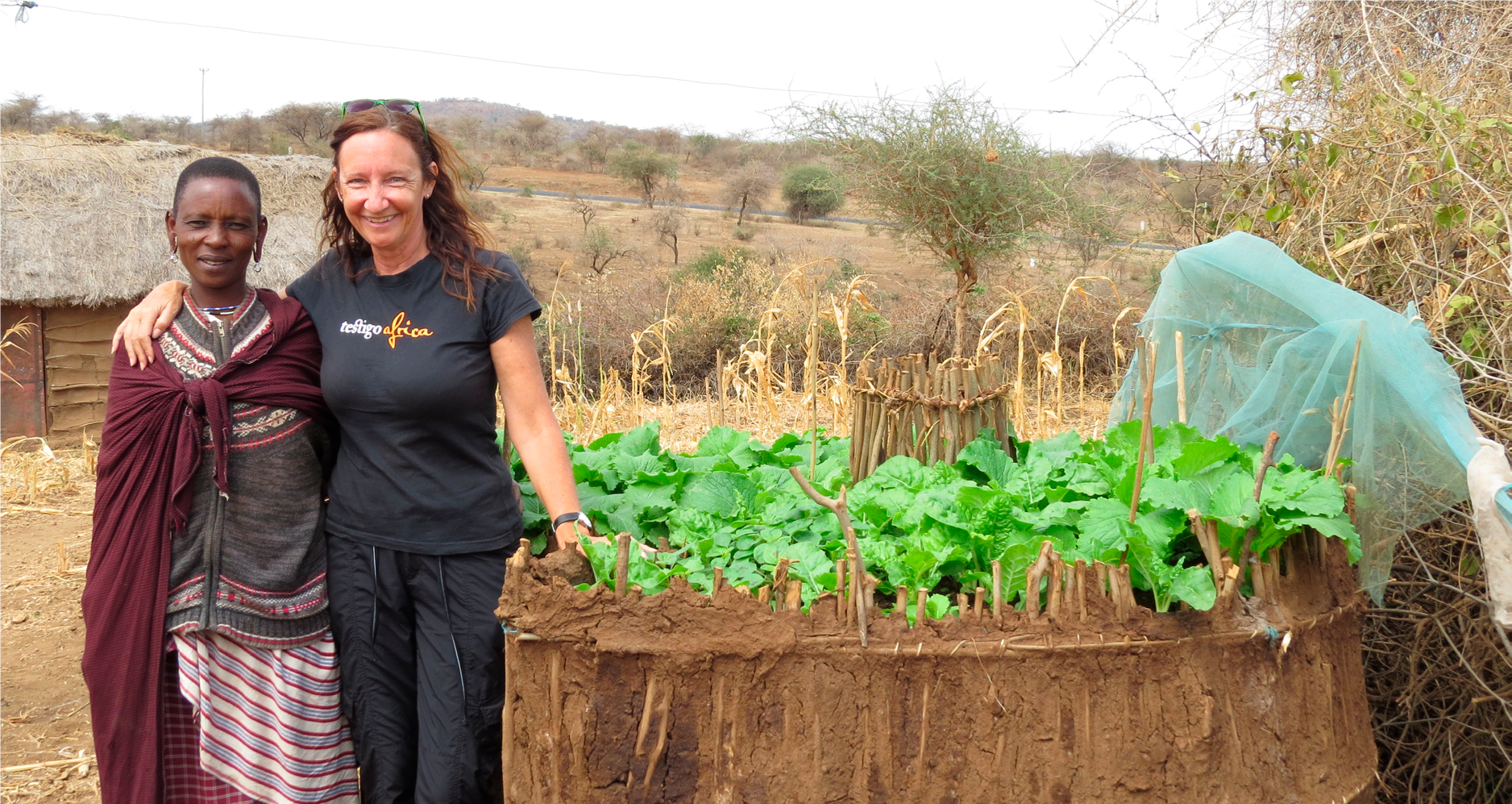 Image of Tracey and a Masai woman in front of a garden