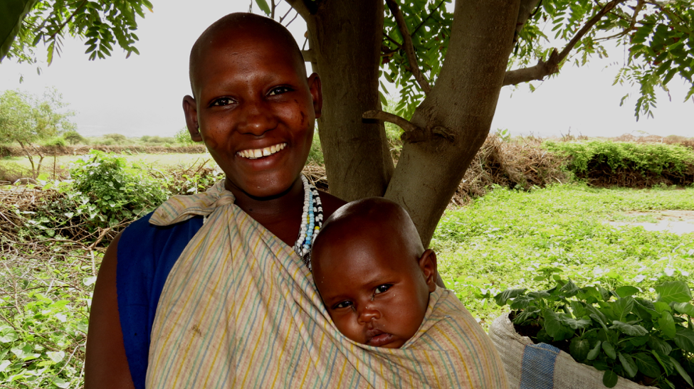 Nosim and her child pictured in front of one of her sack gardens.